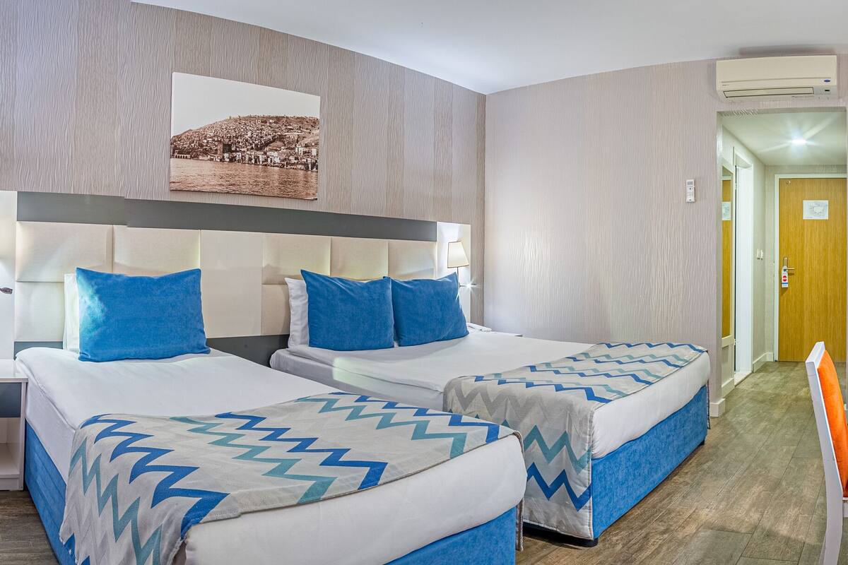 Habitación de hotel con dos camas, un escritorio, una silla y un espejo.