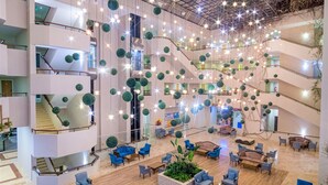 A spacious atrium with multiple levels, a central staircase, and a variety of seating areas. - Justiniano Park Conti (Alanya)