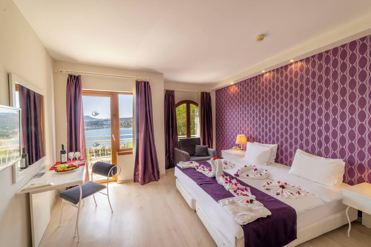 A hotel room with a bed, a desk, a chair, and a view of the outdoors.