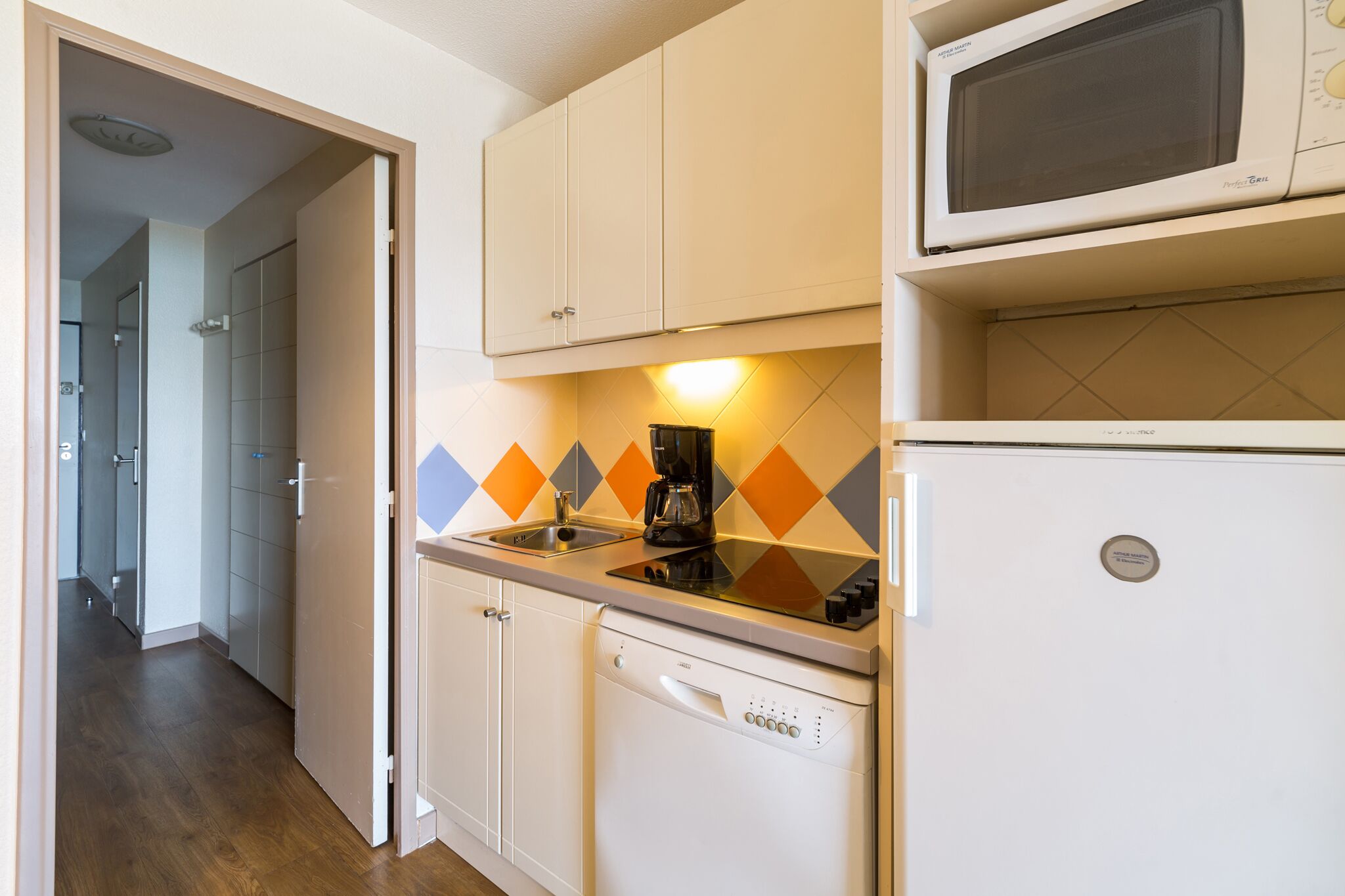 A compact kitchen with a dishwasher, a coffee maker, and a microwave.