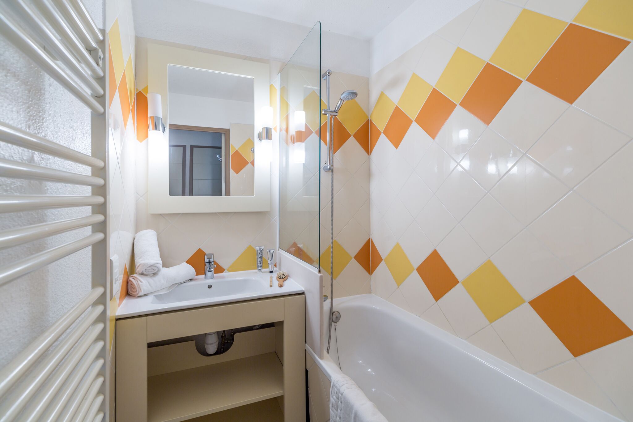 A bathroom with a glass shower enclosure, a white bathtub, and a sink with a mirror above it.