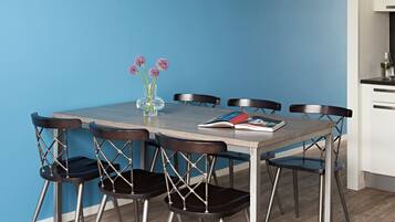 A dining table with six chairs, a vase with flowers, and a magazine.