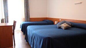 Habitación de hotel con dos camas individuales, un escritorio de madera y una silla.