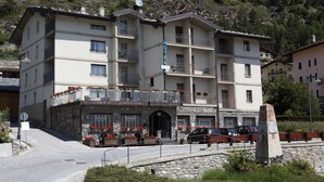 Un hotel de varios pisos con balcones, fachada de piedra y un cartel que indica que es un hotel.