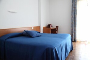 A bedroom with a bed, a wooden nightstand, and a chair. - Hôtel Bellavista (Saint-Nicolas)