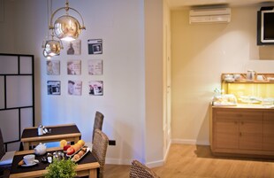 A dining area with a table set for two, a small plant, and a wall with framed pictures.