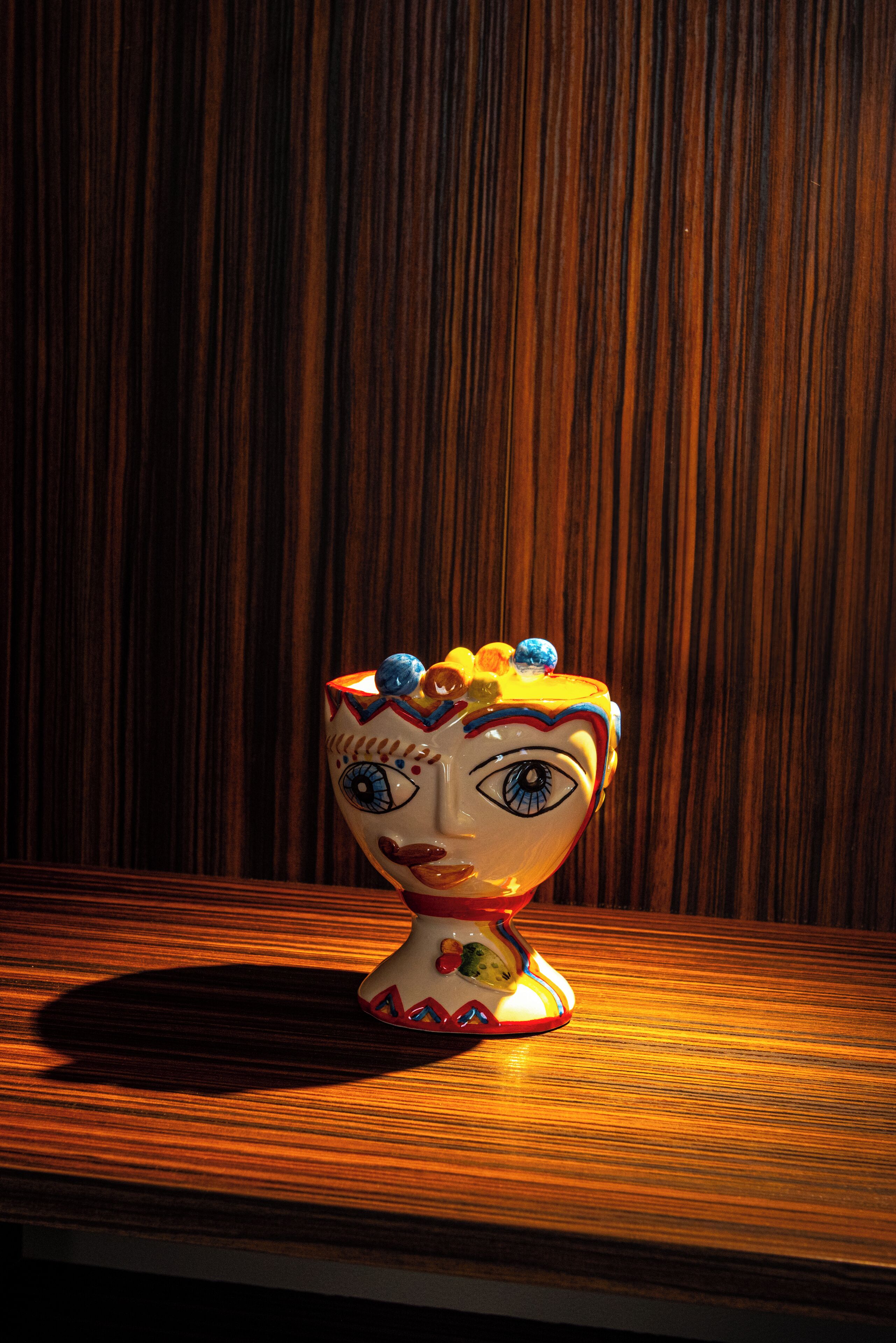 A ceramic figurine on a wooden surface with a wooden background.