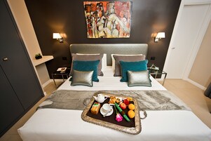 Une chambre d’hôtel avec un grand lit, deux oreillers, un plateau avec des articles pour le petit-déjeuner et un tableau au mur.