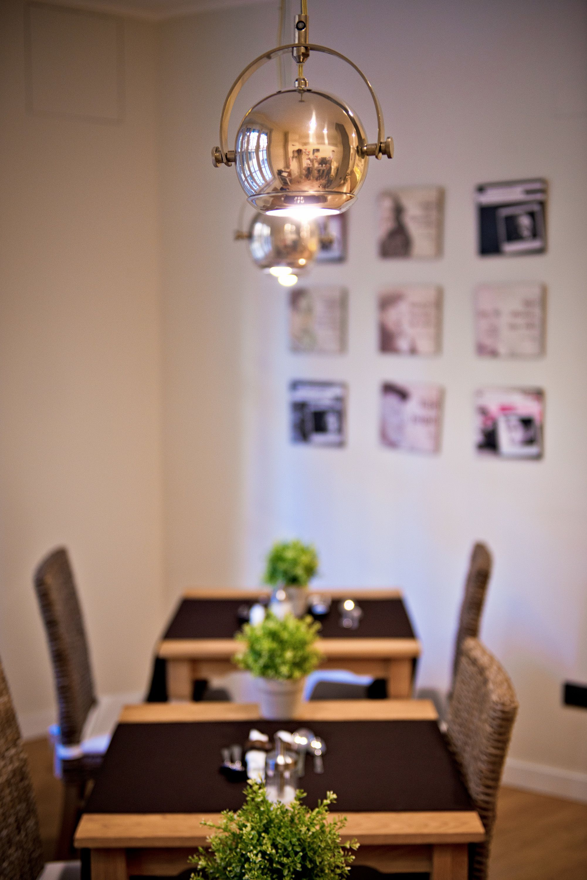 A dining area with a table and chairs, a hanging light fixture, and framed pictures on the wall.