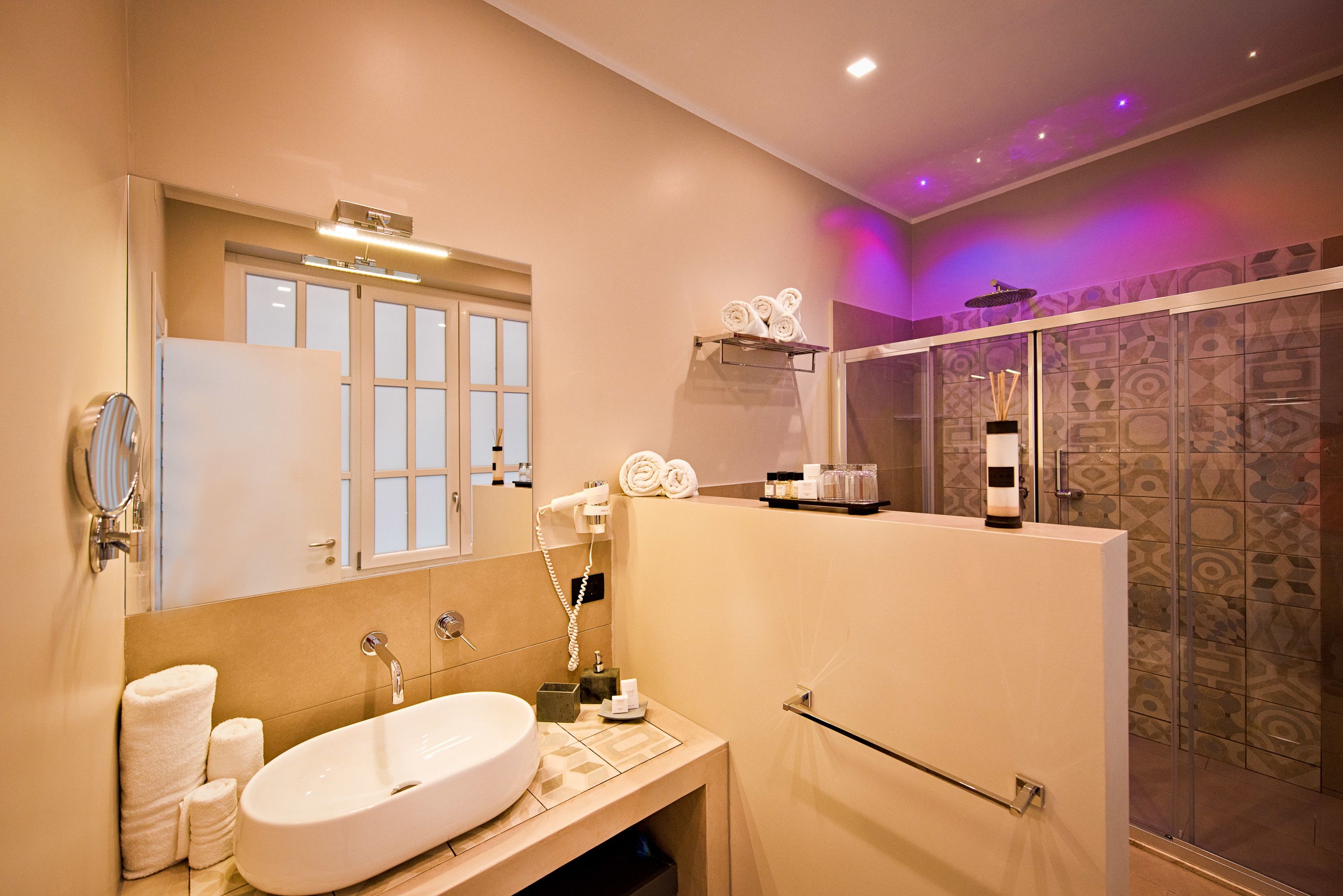 A modern bathroom with a large sink, mirror, and towel rack.