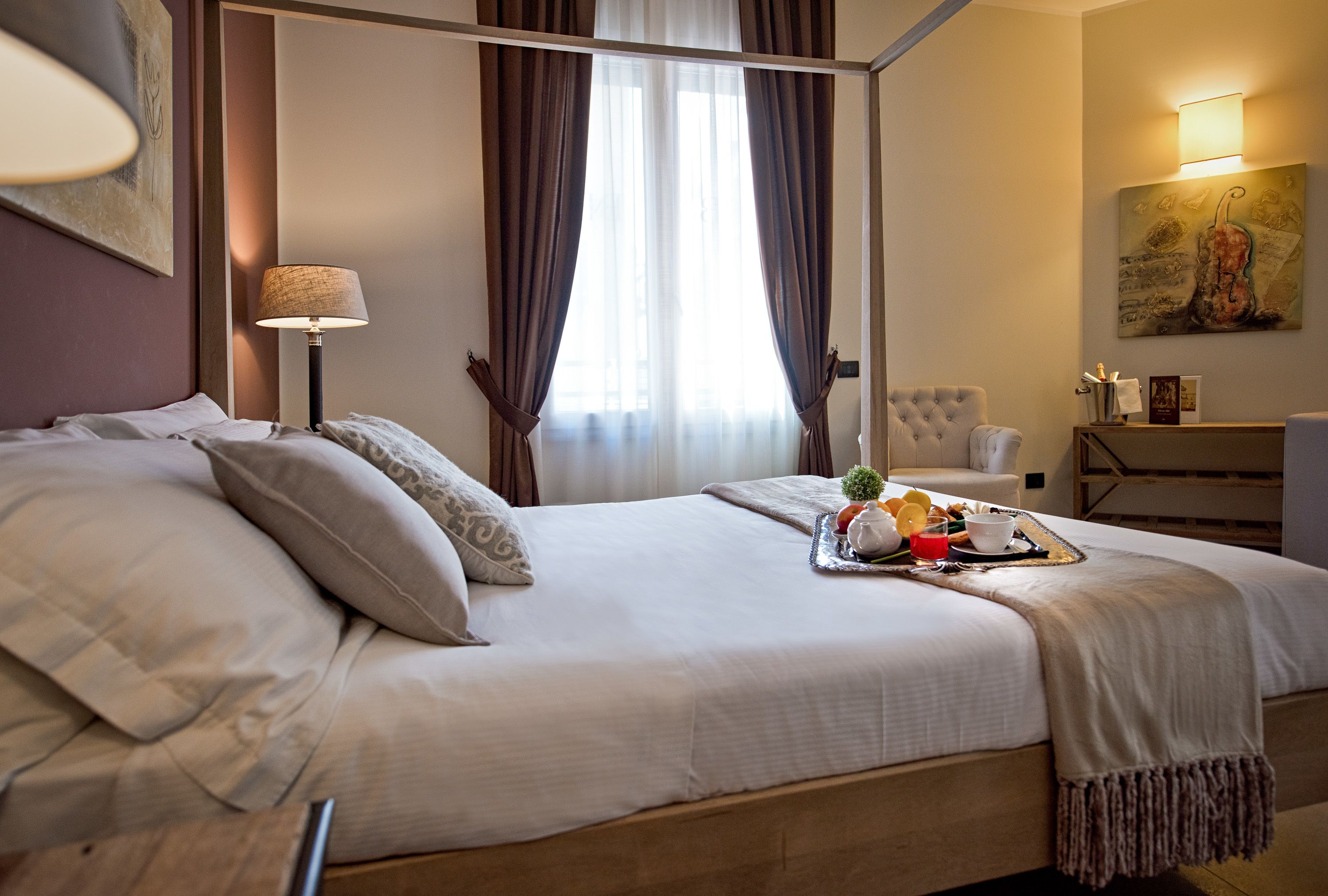 A neatly made bed with pillows, a bedside lamp, and a tray with breakfast items.