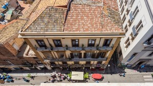 Ein mehrstöckiges Gebäude mit Ziegeldach, Balkonen und einem Innenhof mit Personen und Sitzgelegenheiten.