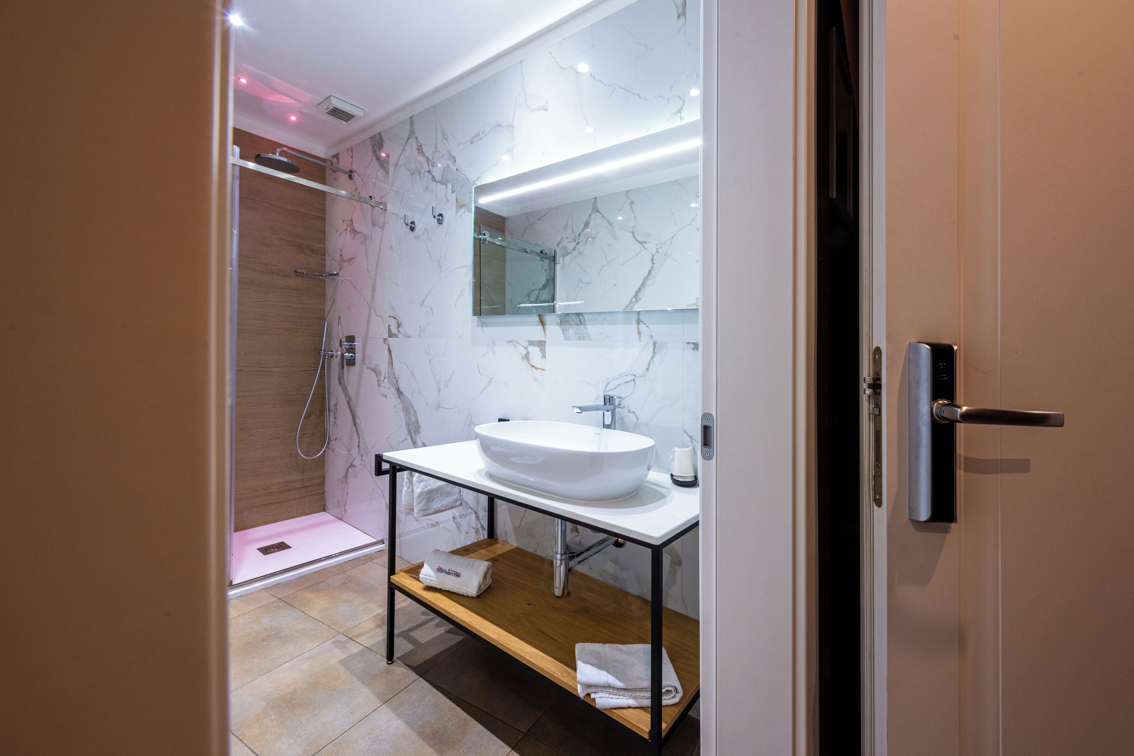 Une salle de bain moderne avec un meuble-lavabo en marbre, une cabine de douche en verre et un banc en bois.