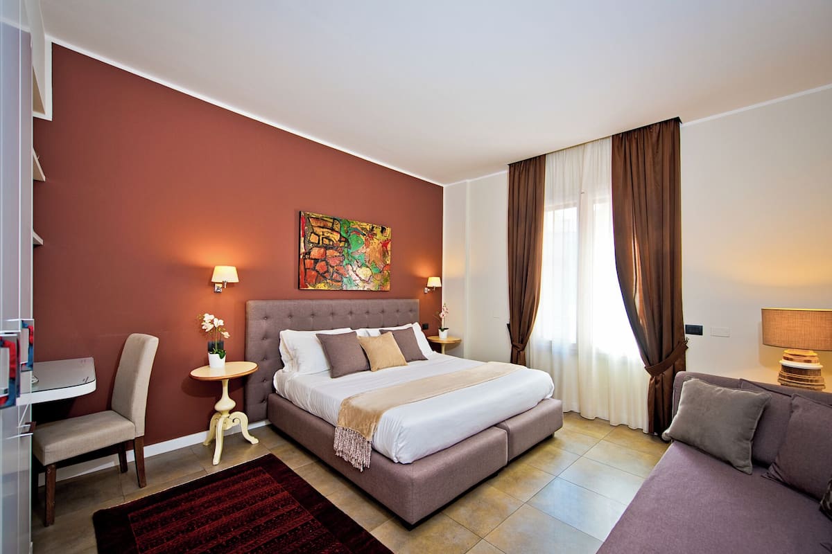 Une chambre d’hôtel moderne avec un grand lit, un bureau, une chaise et un canapé.