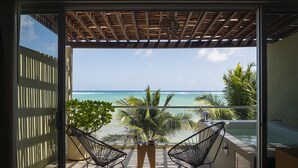 A balcony with two chairs, a table, and a view of the ocean. - Mereva Tulum (Tulum)
