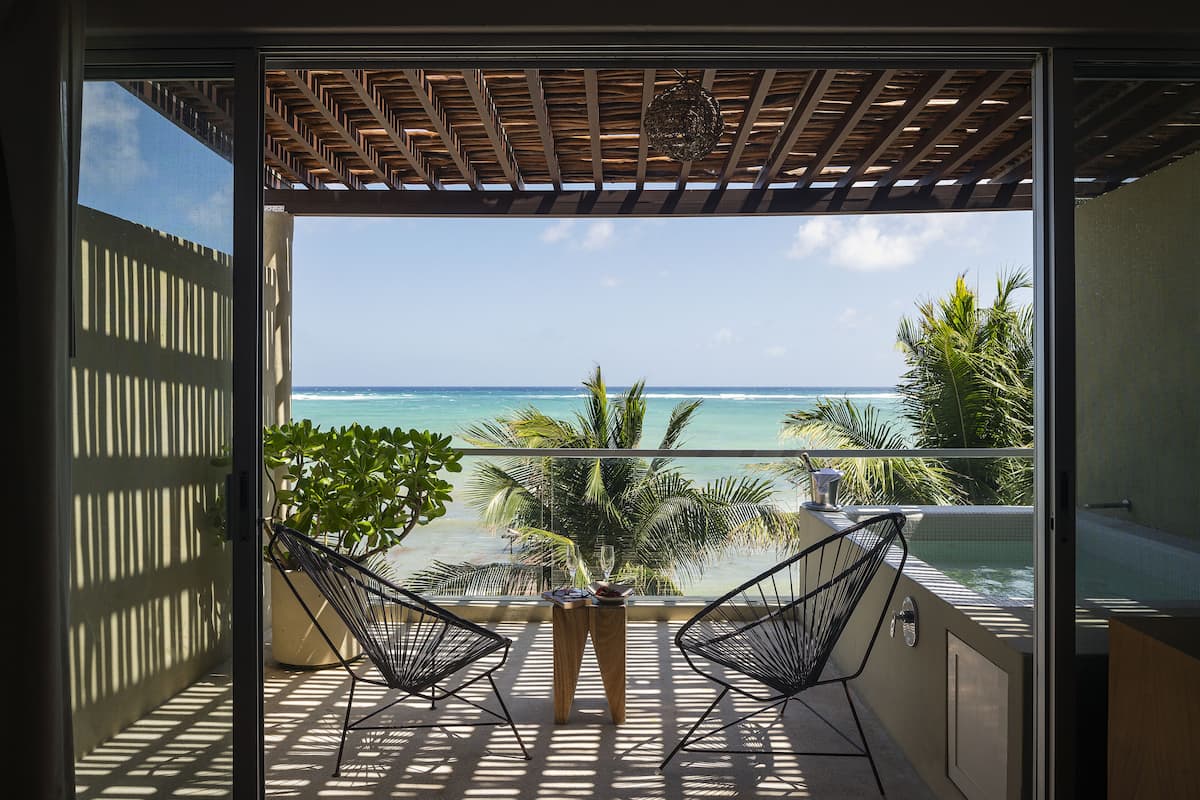 A balcony with two chairs, a table, and a view of the ocean.