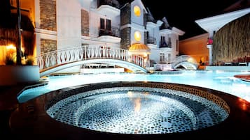 Relax by the pool surrounded by a decorative railing and a stunning backdrop of a multi-story building with balconies.