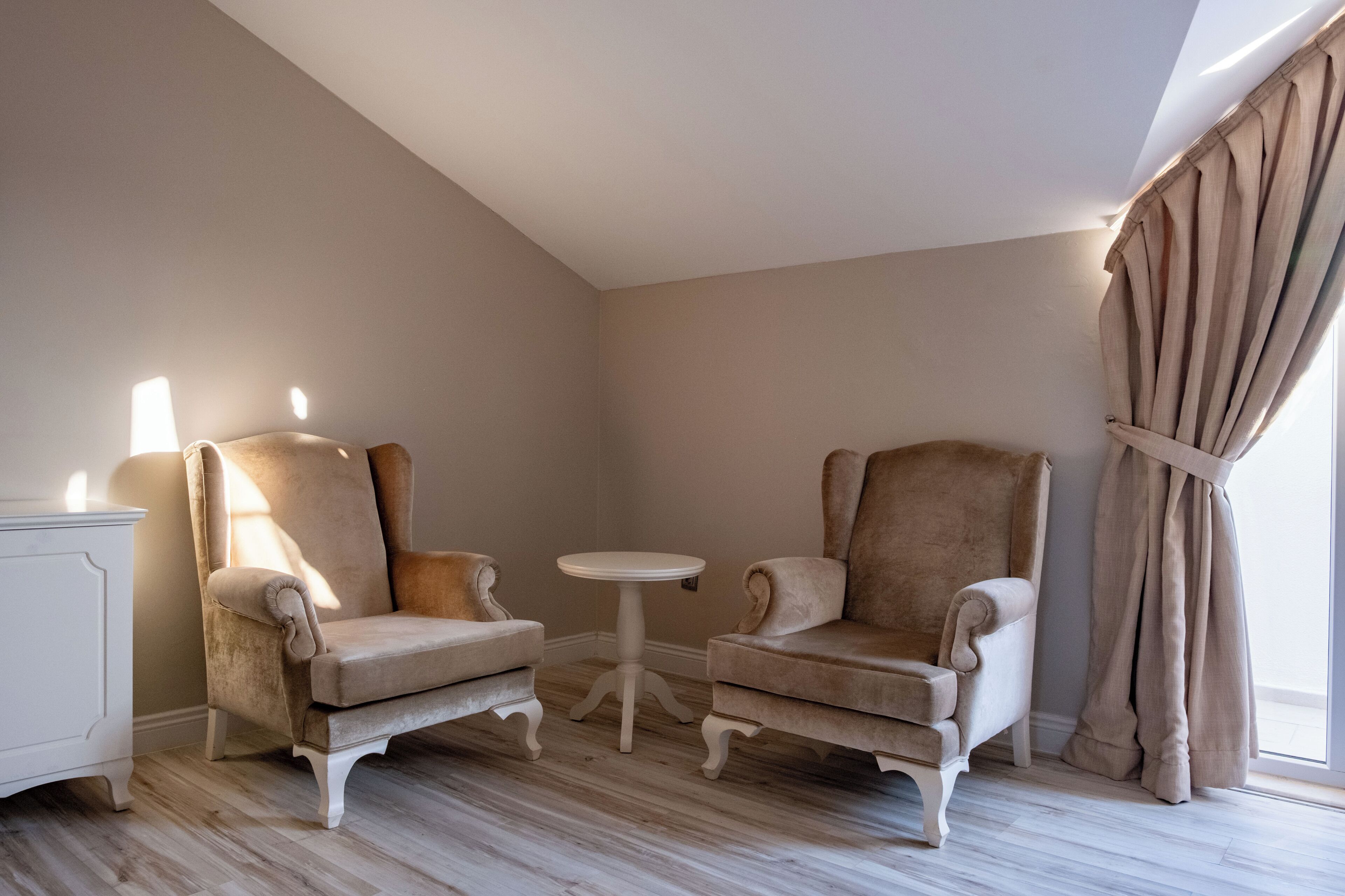 Une pièce comprenant deux fauteuils, une petite table ronde et un meuble blanc.