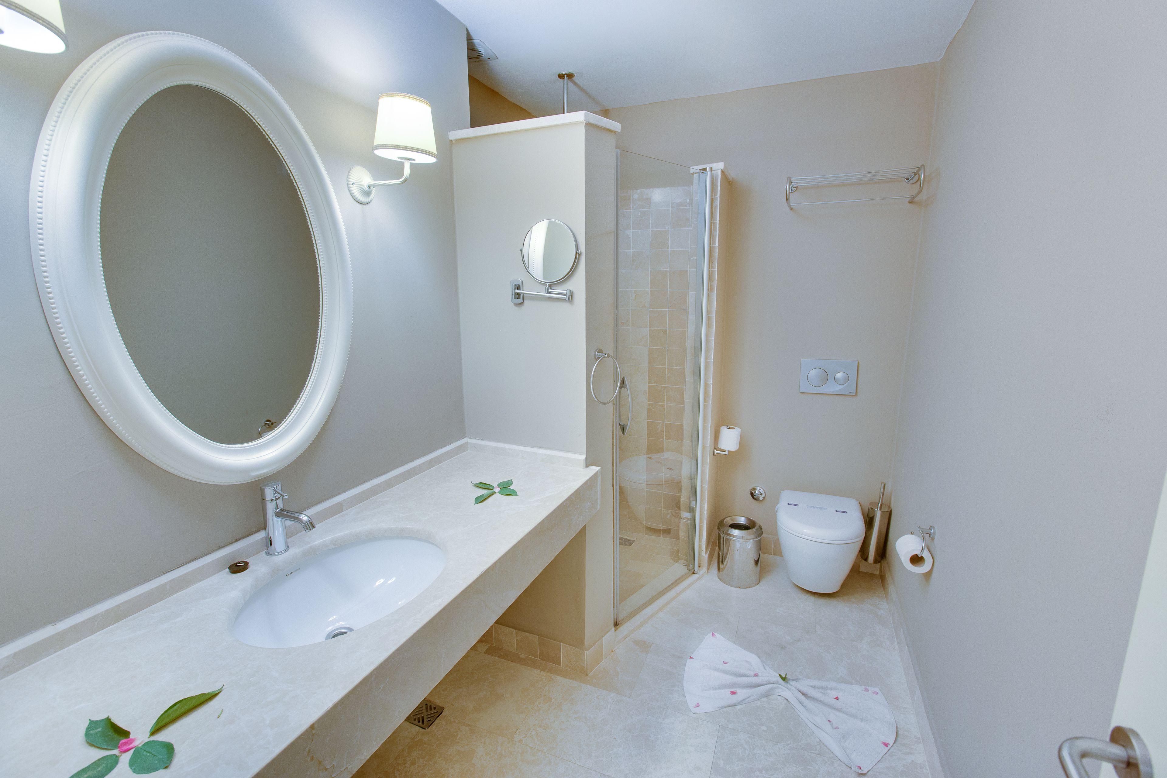 A bathroom with a sink, mirror, toilet, and shower.