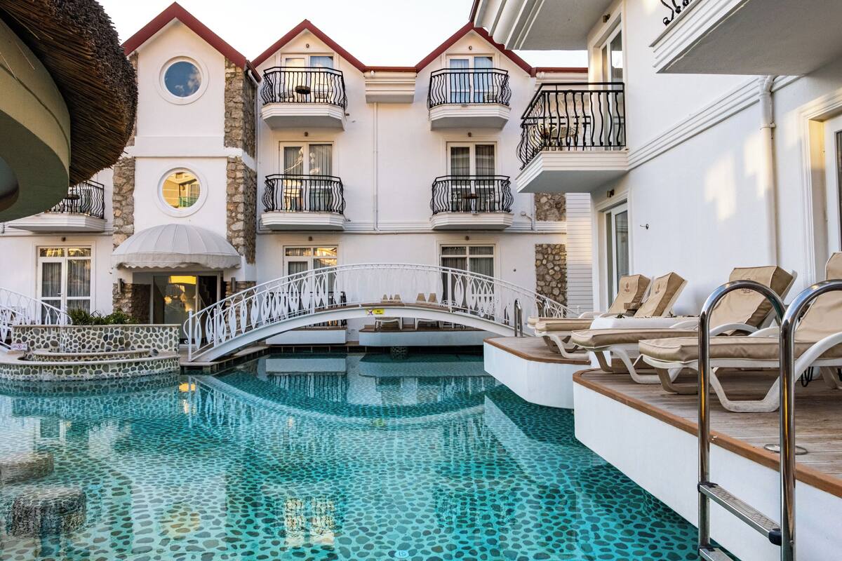 A hotel with a swimming pool, a bridge, and multiple balconies.