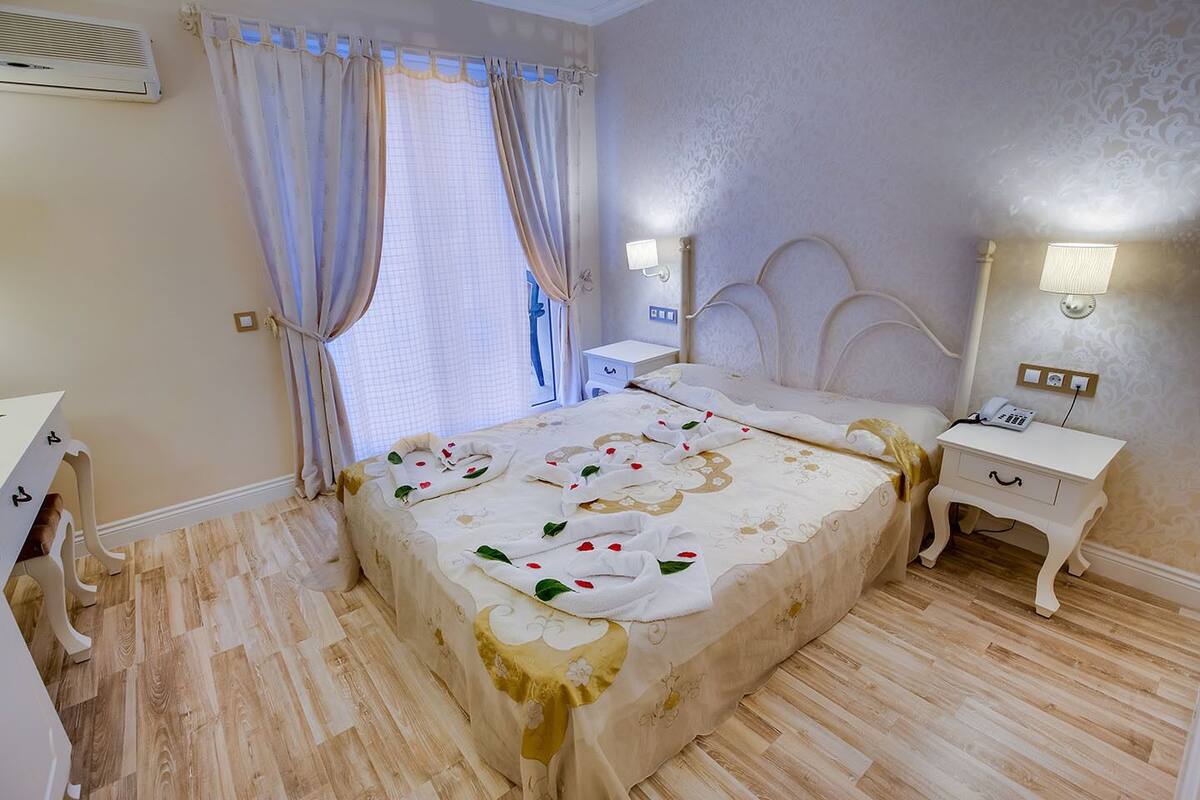A bedroom with a bed, bedside tables, a lamp, and a window with curtains.