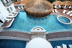Una piscina grande con sillas de descanso y sombrillas, rodeada por una terraza.