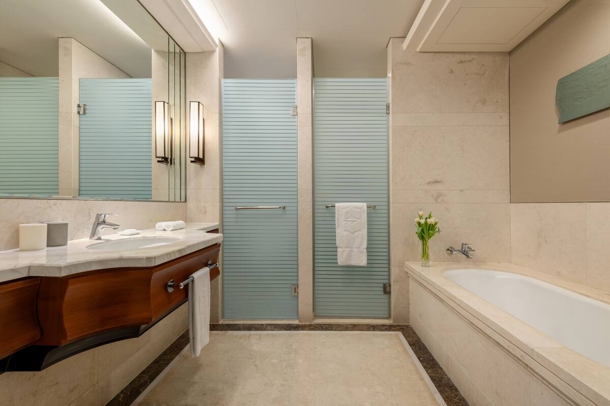 A modern bathroom with a large mirror, a sink, a bathtub, and a shower area.