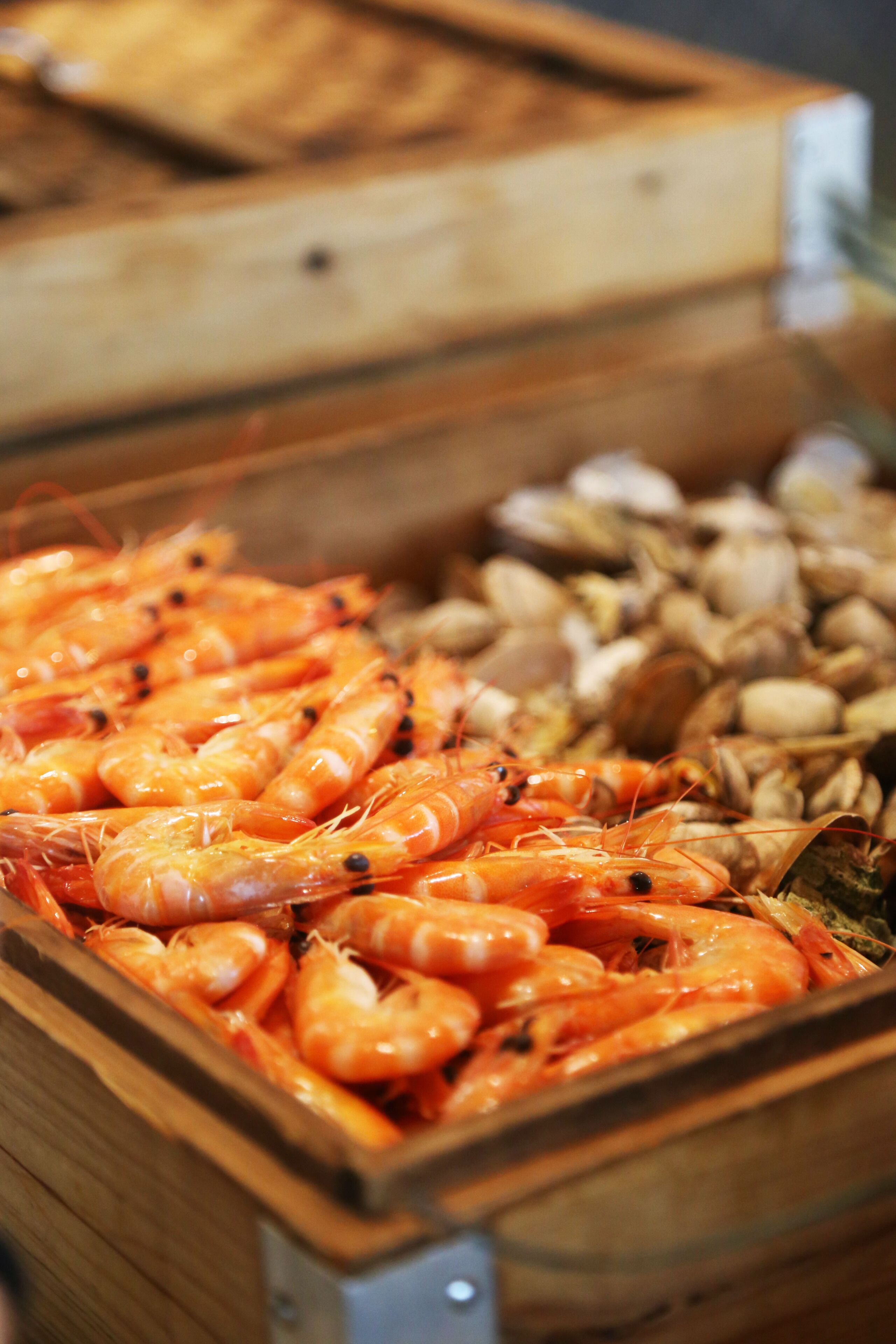A wooden box filled with cooked shrimp and clams.