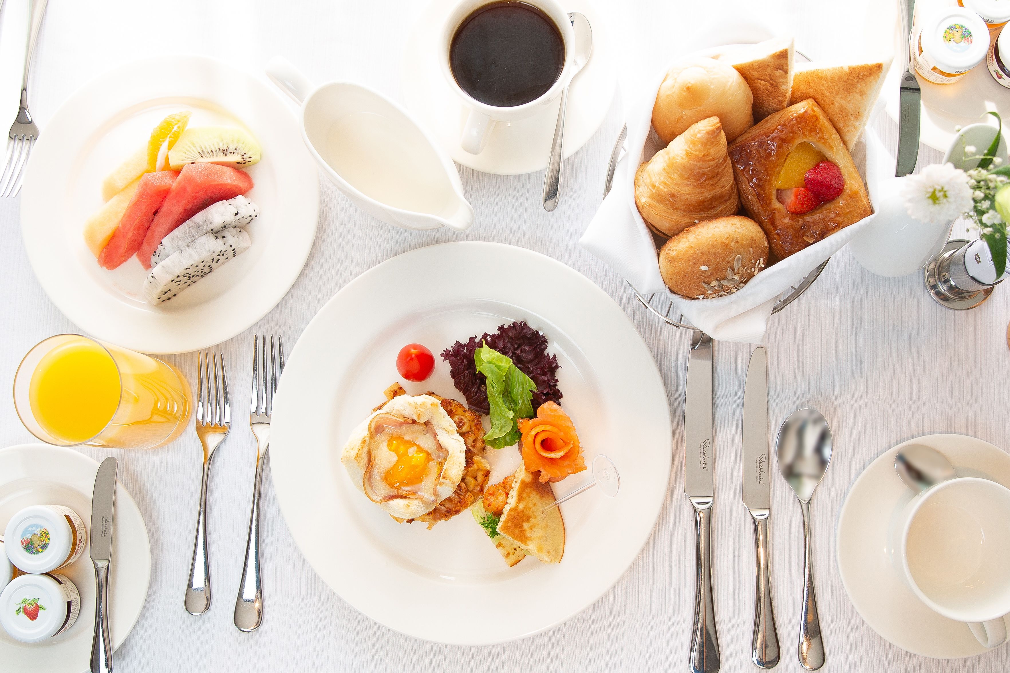 Une table mise pour le petit-déjeuner, avec des assiettes remplies de nourriture, des couverts et une tasse de café.
