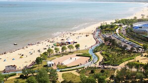 Ein Strand mit Parkplatz und einem Park, der eine Spielplatz beinhaltet.