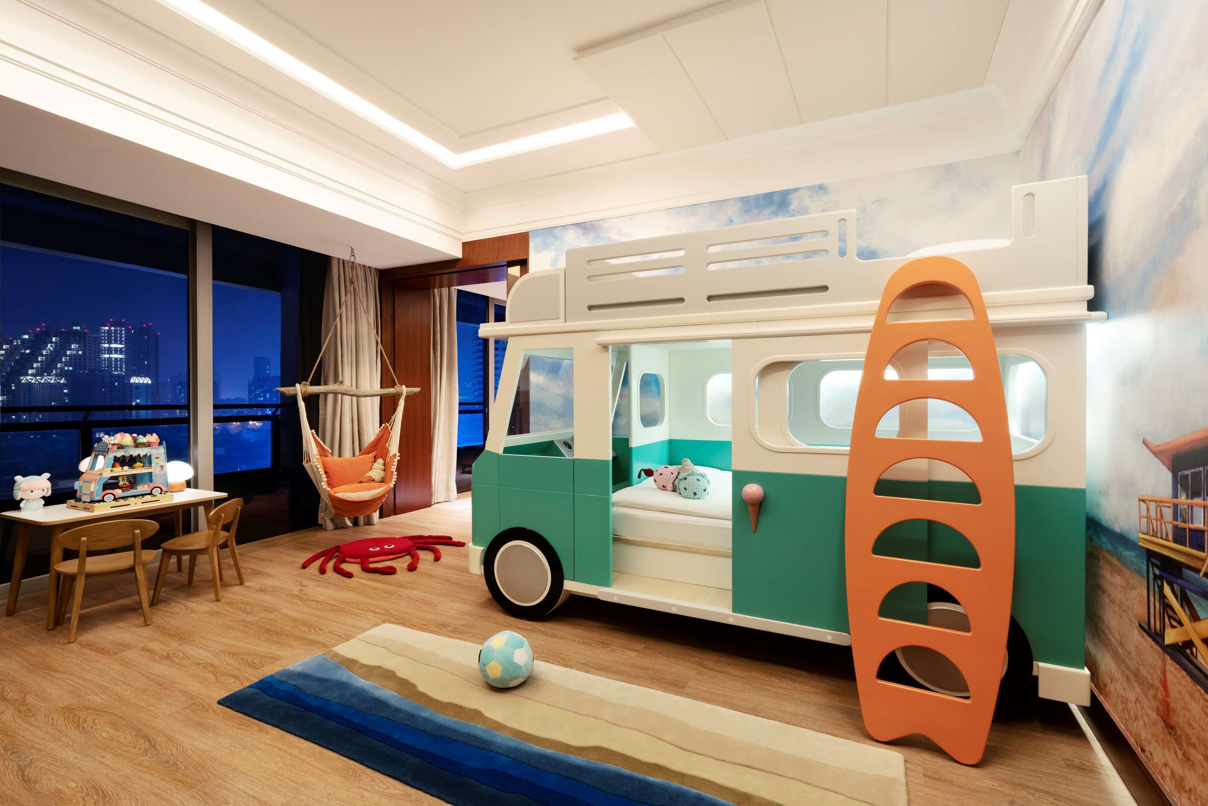 A children's playroom with a toy bus, a hanging chair, and a beach-themed rug.