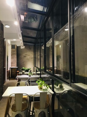 Un espace de restauration moderne avec des murs en verre, des tables en bois et des chaises.