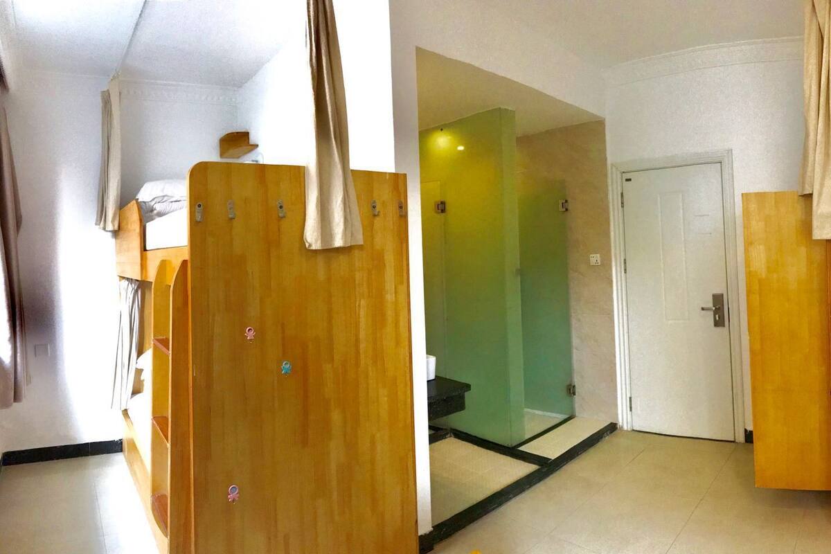 A bunk bed room with a wooden door, a green wall, and a white ceiling.