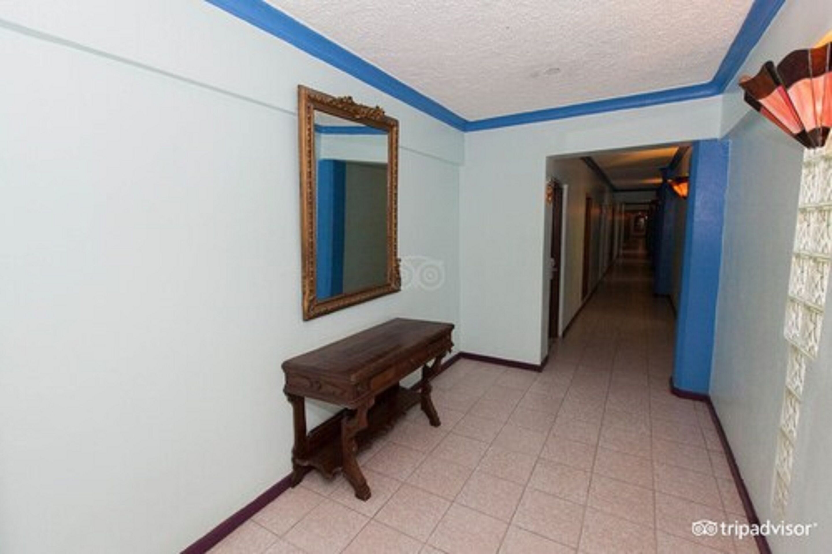 A hallway with a wooden bench, a mirror, and a patterned wall.