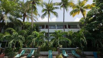 A hotel with a pool, palm trees, and lounge chairs.