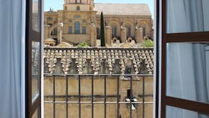 Vista a través de una ventana que muestra un edificio con tejado de azulejos, una cúpula y ventanas de arco.