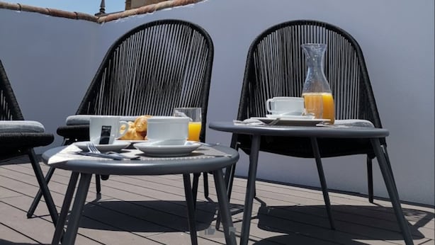 Una terraza con dos sillas y una mesa, con vistas a una histórica torre campanario.