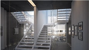 Un interior moderno con una escalera, paredes de vidrio y obras de arte enmarcadas.