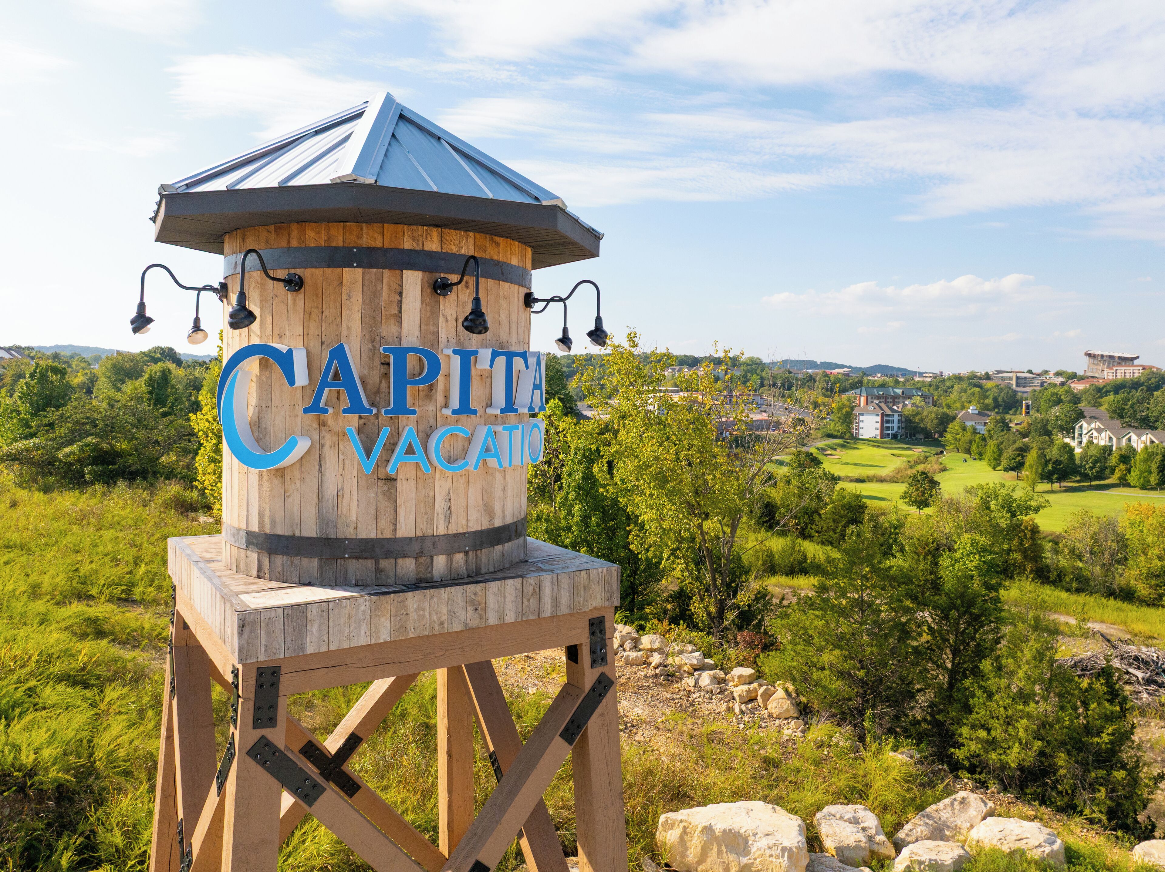 Una estructura de madera con el letrero "CAPITA VACATIO", rodeada de vegetación y vistas a un pueblo.