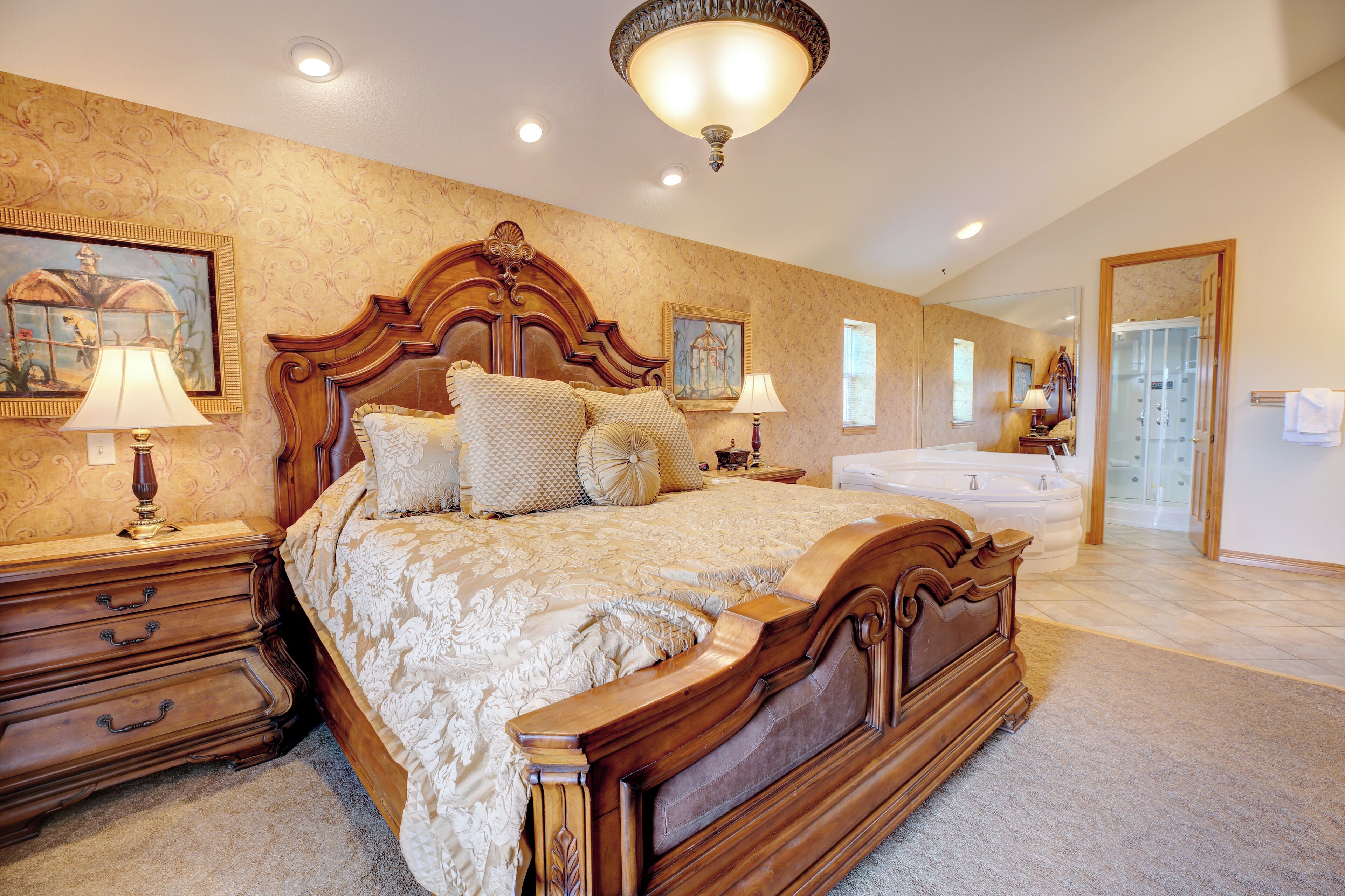 A spacious bedroom with a large bed, a wooden nightstand, a bedside table, and a bathroom with a bathtub and shower.