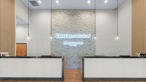 Zona de recepción con pared de piedra, dos mostradores de recepción, lámparas colgantes y suelo de madera.