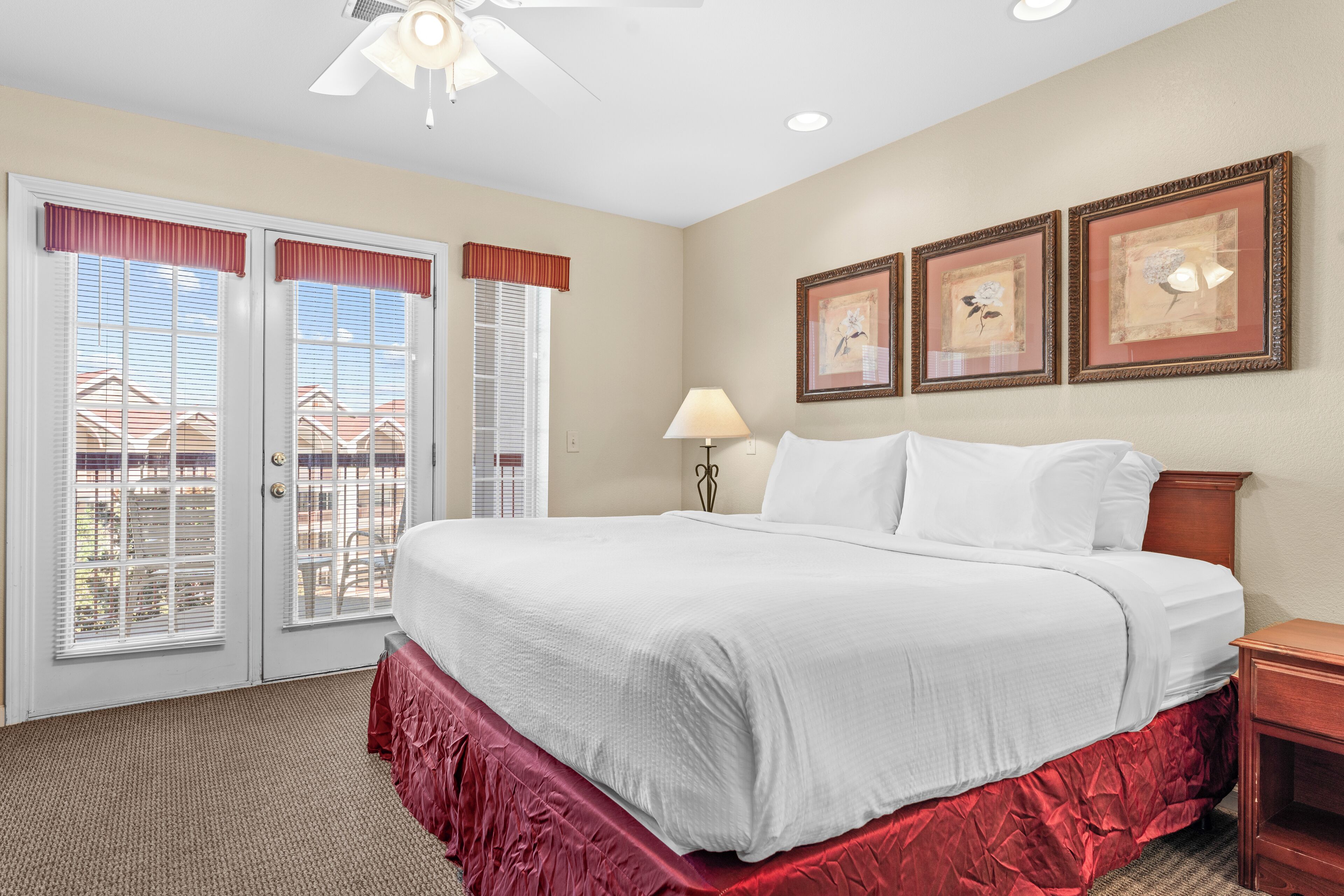 A hotel room with a large bed, a nightstand, a lamp, and two framed pictures on the wall.