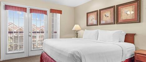 A hotel room with a large bed, a nightstand, a lamp, and two framed pictures on the wall.