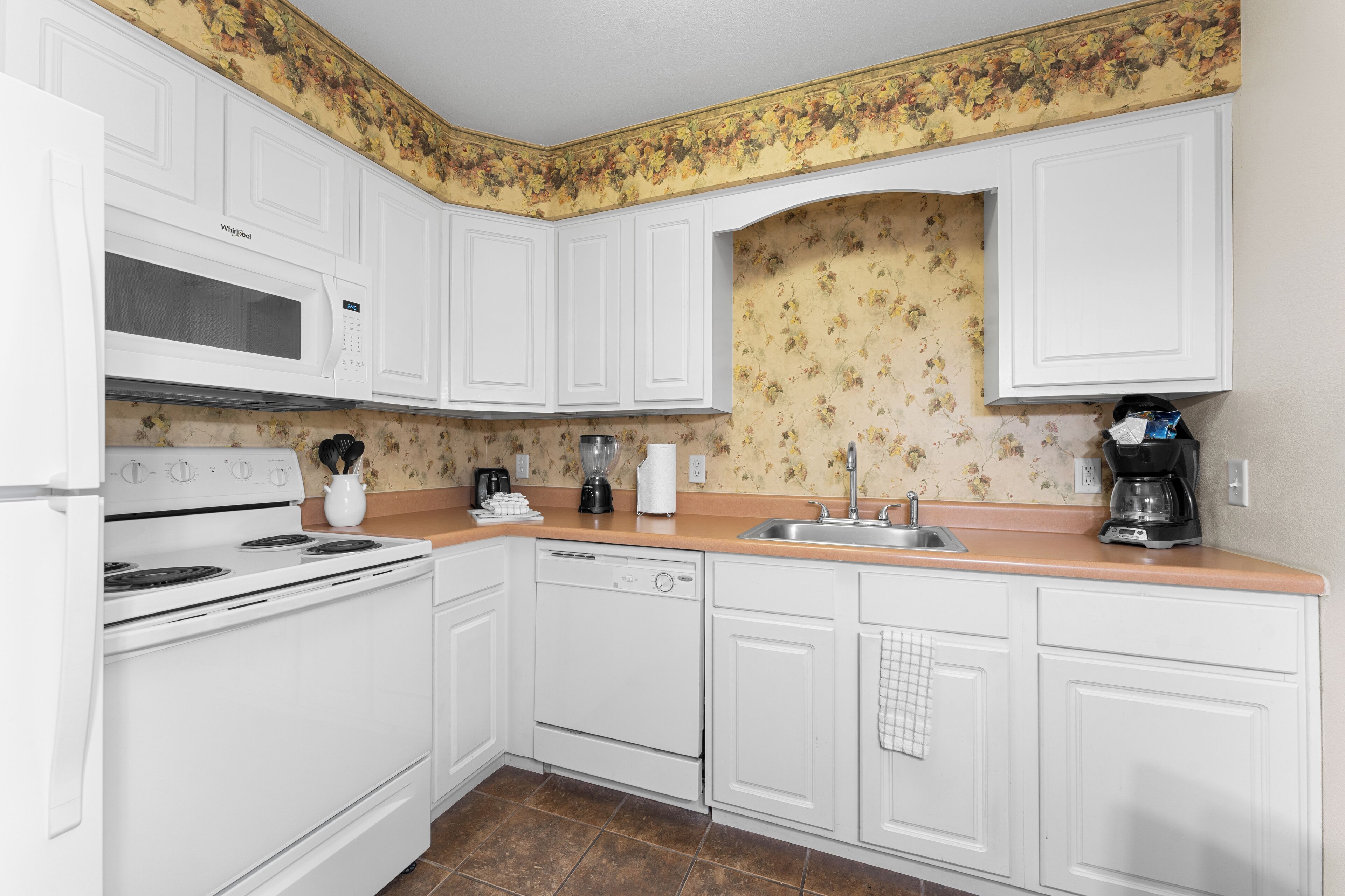 A kitchen with white cabinets, a microwave, stove, dishwasher, and a sink.