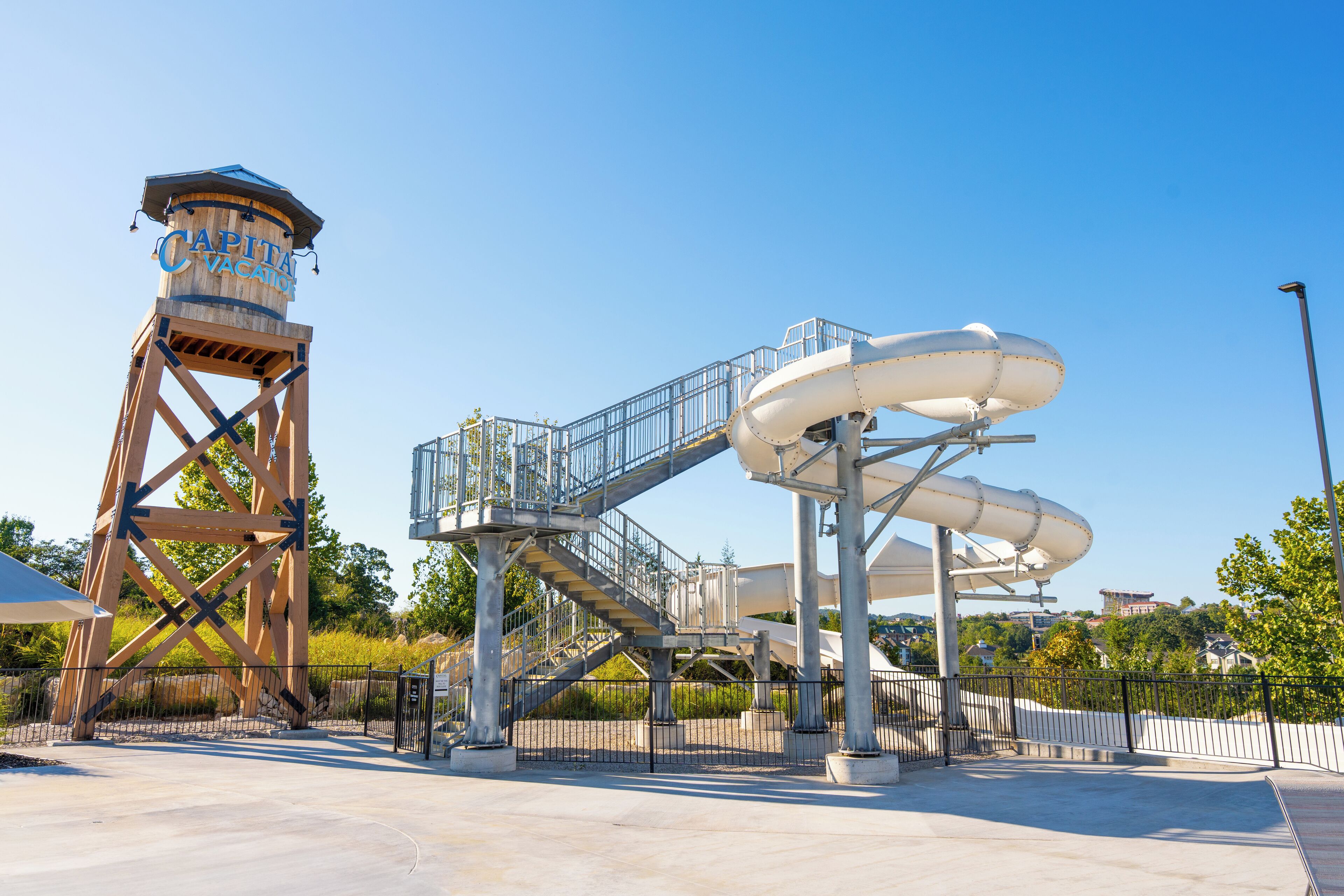 A water park with a tall wooden tower labeled "Capital Vacation" and a large water slide structure.