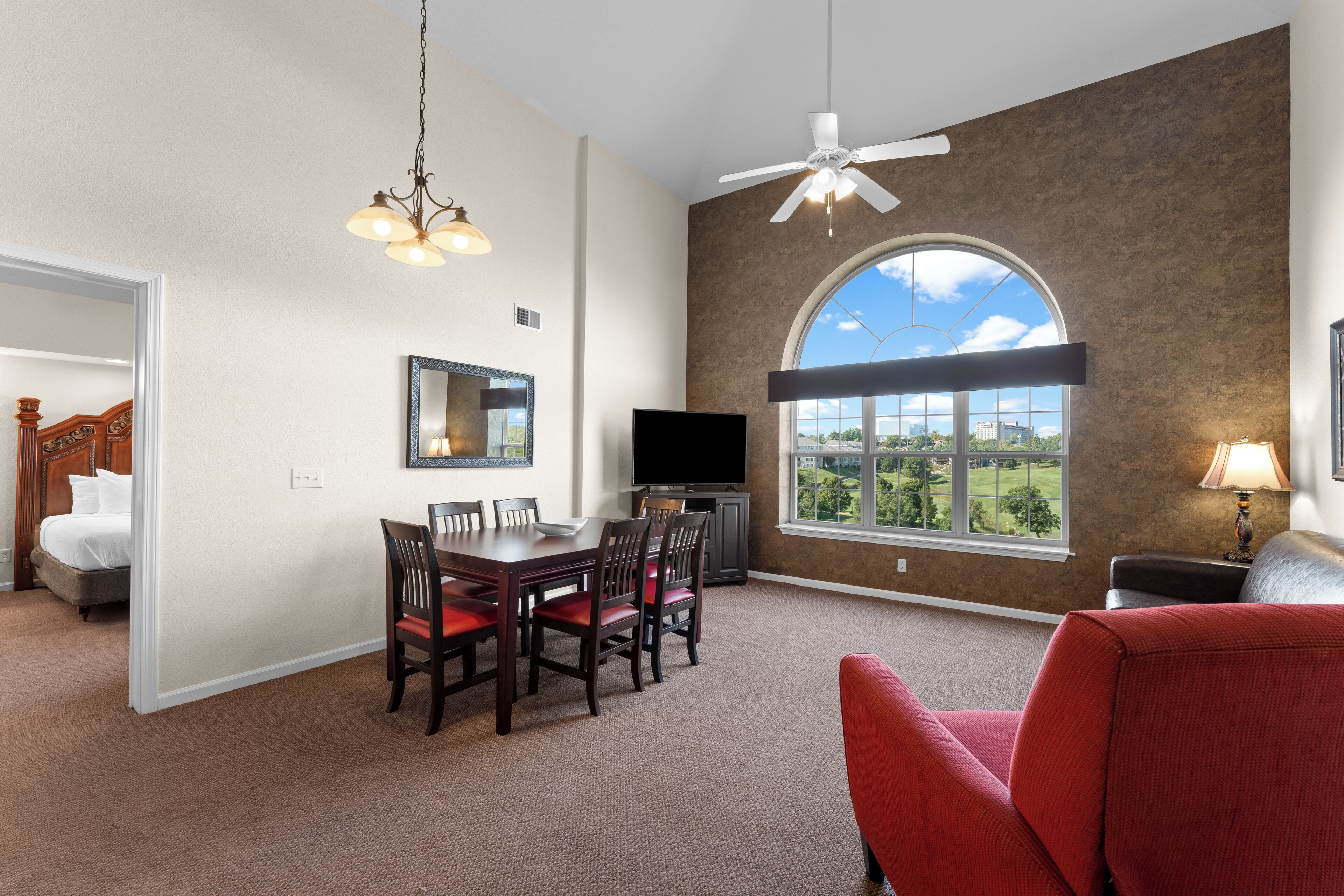 A spacious room with a dining table, chairs, a TV, and a large window with a view.