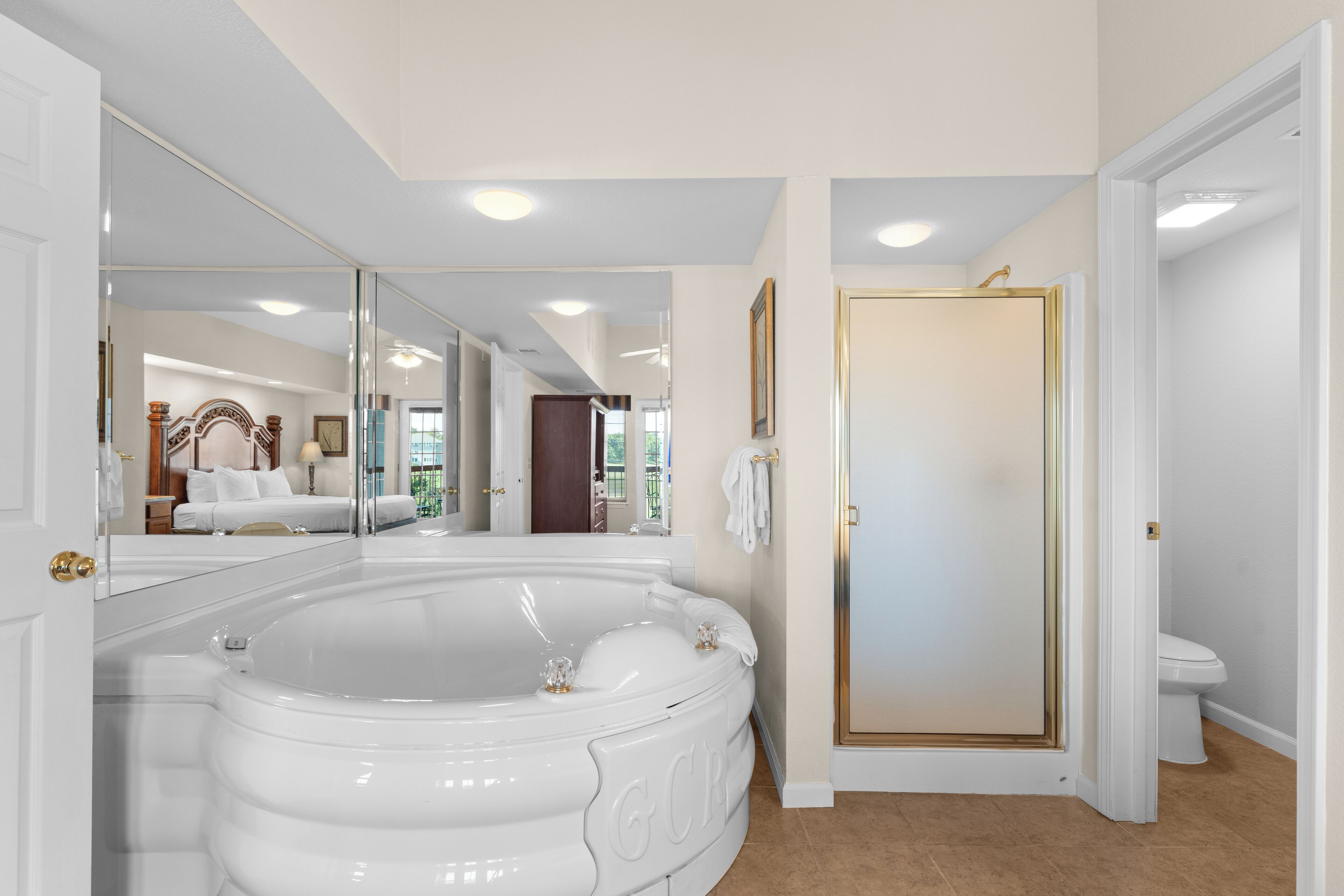Ein Badezimmer mit einer großen weißen Badewanne, einer Toilette und einer Tür mit goldener Rahmung.