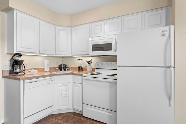 A kitchen with white cabinetry, a built-in microwave, a stove, and a refrigerator. - Grand Crowne Resort (Branson)
