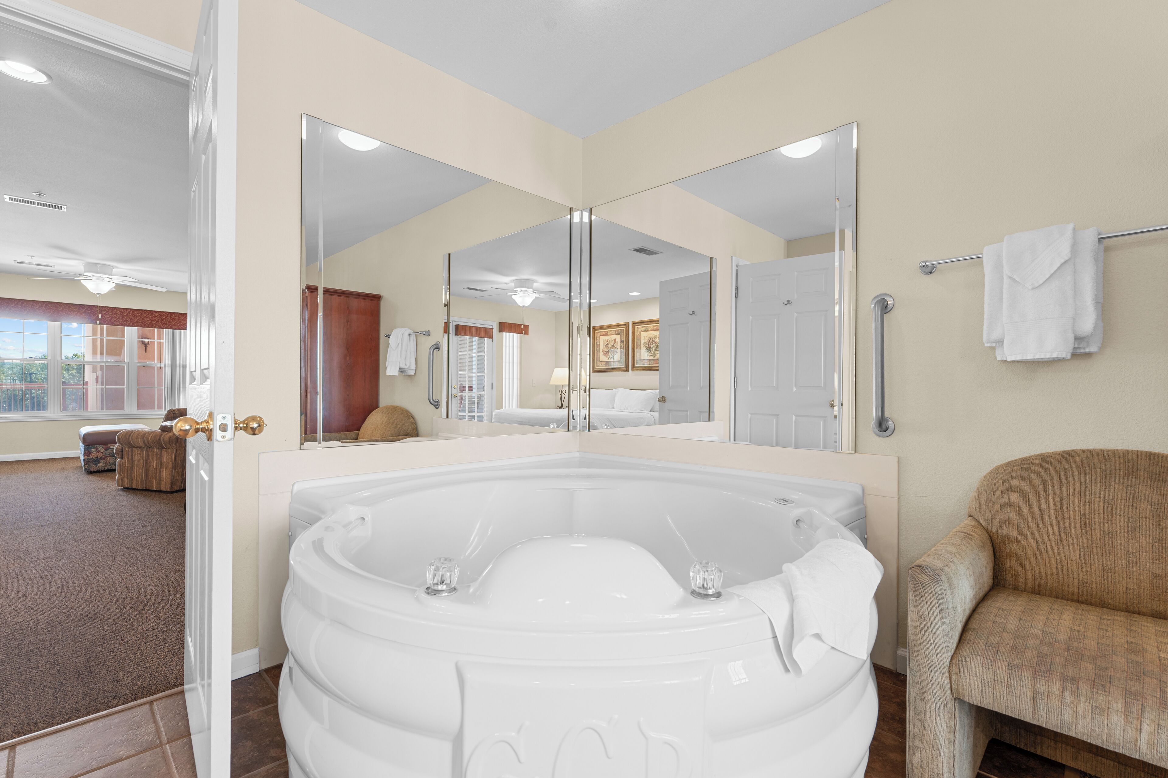 A bathroom with a large bathtub, a mirror, a towel rack, and a chair.
