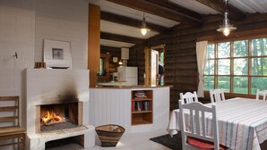 A cozy log cabin interior with a fireplace, wooden furniture, and a view of the outdoors. - Koivulan Kartano (Lohja)